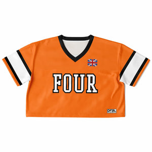 An orange short-sleeve cropped jersey-style top with a black and white V-neck, white and black striped sleeves, large 'FOUR' lettering across the chest, a small Union Jack flag graphic on the upper right chest, and a small 'DFGL' logo patch near the lower right hem, shown on a plain white background.